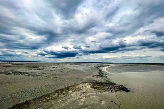 A serene beach with calm waters beneath a cloudy sky.