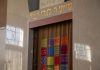 A synagogue ark with colorful tapestry curtains and Hebrew inscriptions.
