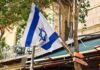 An Israeli flag zip tied to a slender tree
