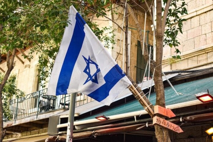 An Israeli flag zip tied to a slender tree