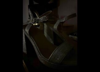A pair of silver heels gleam in the dark.