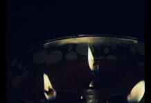 A close-up shot of a lit three-wick candle