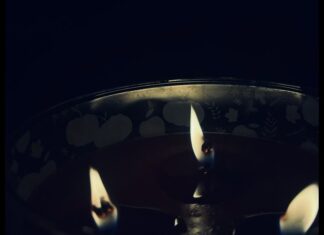 A close-up shot of a lit three-wick candle
