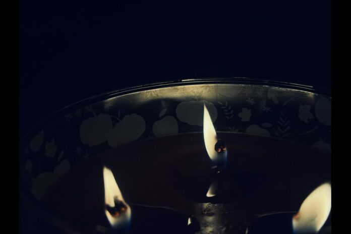 A close-up shot of a lit three-wick candle