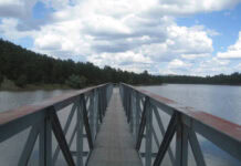 A long pier stretches out into a gray-blue lake. It doesn't quite reach the opposite shore.