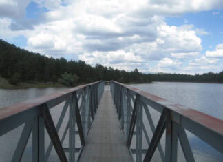 A long pier stretches out into a gray-blue lake. It doesn't quite reach the opposite shore.
