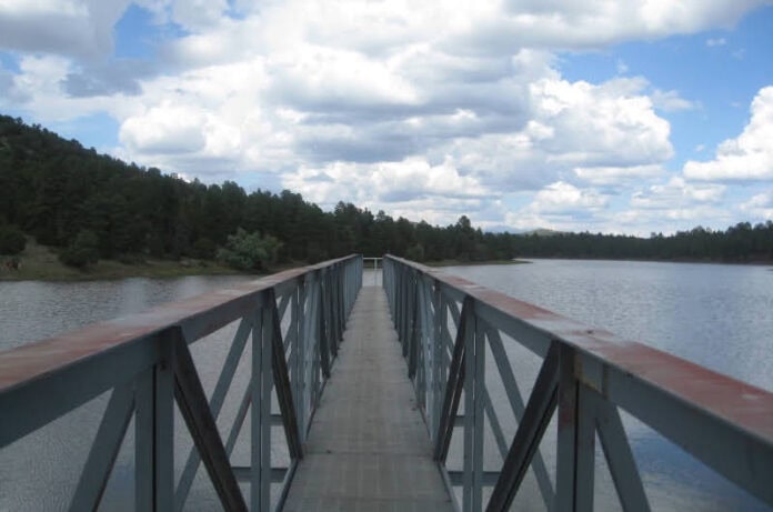 A long pier stretches out into a gray-blue lake. It doesn't quite reach the opposite shore.