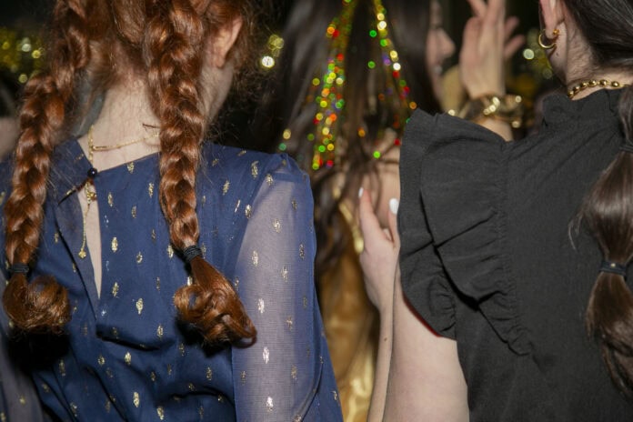 Two young girls, all dressed up, dance at a bat mitzvah.