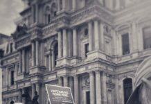 A crowd of people in front of a stately building in Philadelphia. One person holds up a sign that says "Hate Has No Home Here."