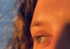 Unpacking the Myth of the Mystic Feminine A close up shot of a woman's eyes looking to the side with the sun highlighting the lighter parts in her hair and eyes.