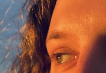Unpacking the Myth of the Mystic Feminine A close up shot of a woman's eyes looking to the side with the sun highlighting the lighter parts in her hair and eyes.