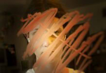 I Am God’s Teenage Daughter Girl looking into a mirror. Red marks drawn on the glass cover her face.