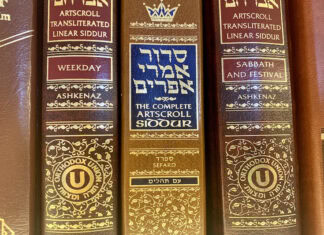 Yismechu A close-up of three siddurim (Jewish prayer books) in shades of red and brown with gold-foiled Hebrew letters on the spine.
