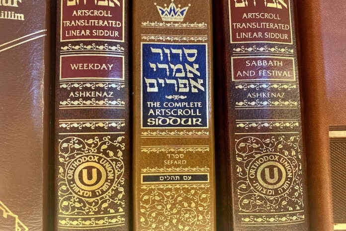 Siddurim A close-up of three siddurim (Jewish prayer books) in shades of red and brown with gold-foiled Hebrew letters on the spine.