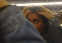 The Way I Look A teen girl is running her fingers through her hair while looking at her reflection in a slightly blurry mirror. Her arm covers one of her eyes and the bottom of her face, leaving only the top of her face visible.